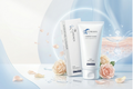 Curenex Hydrating Cleanser skincare tube and box displayed on a reflective surface with pink roses and petals, set against a soft blue and white abstract background with water droplet graphics.
