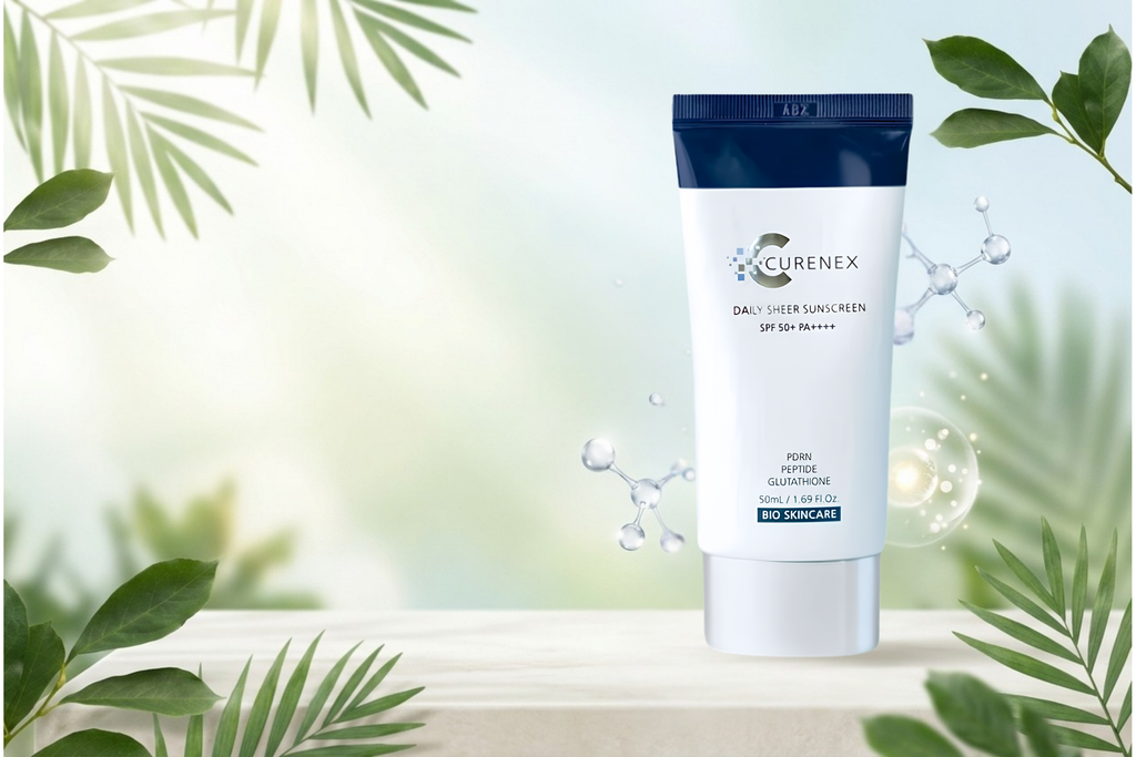 Curenex Daily User Sunscreen SPF 50 sunscreen tube standing on a light surface with decorative green leaves and water droplets around it.
