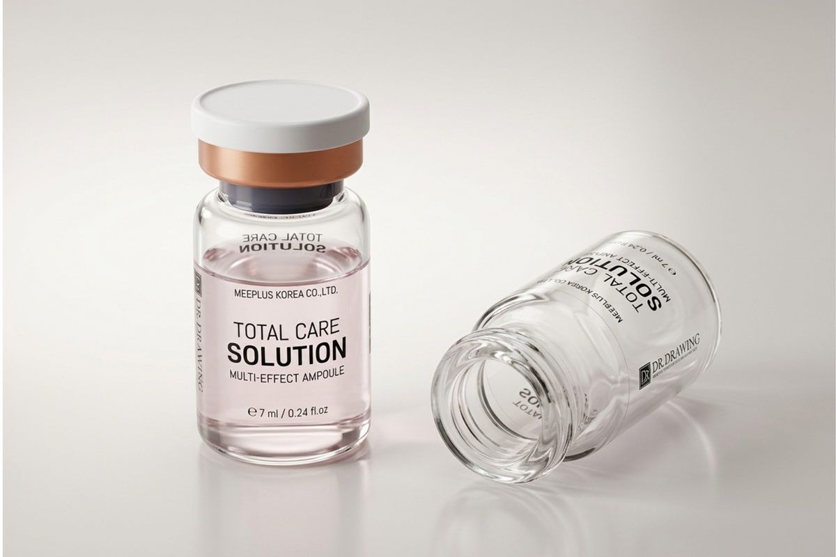 A clear glass ampoule bottle labeled 'TOTAL CARE SOLUTION' with a white cap and metallic rose-gold collar, standing upright next to another tipped-over glass ampoule on a light gray reflective surface.