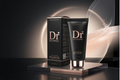 A black cosmetic tube and matching black box for Dr. Drawing Brightening Peeling Gel, displayed on a reflective metallic pedestal against a dark background with soft glowing circular light effects.