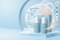 Three skincare bottles and two matching boxes from Niacinamide 15% by La Mer, displayed on a light blue pedestal with floating water droplets and text callouts on a clean pale blue studio background.
